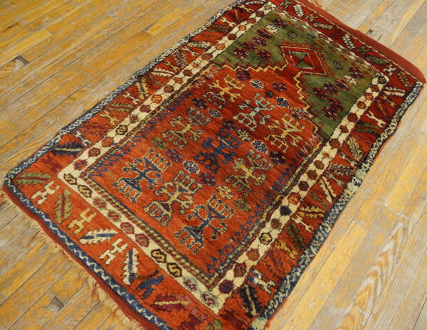 A thick-pile tribal rug featuring rustic red, olive green, and blue geometric patterns on distressed wood floors.