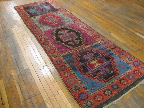 Geometric runner rug featuring bold blue, magenta, red, and black panels on distressed hardwood plank flooring.