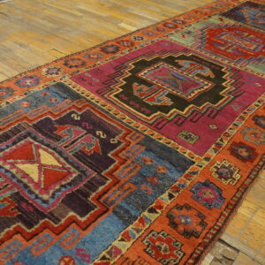 Long geometric runner in bright magenta, blue, red, and orange tones lays on worn wood floors.