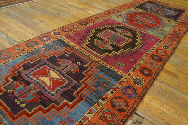 Long geometric runner in bright magenta, blue, red, and orange tones lays on worn wood floors.