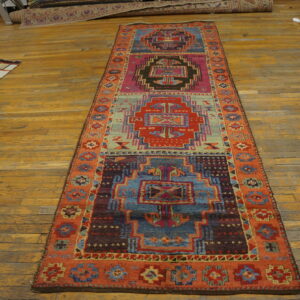 Vibrant geometric runner rug with teal, magenta, and rust colors displayed on rustic wood floors.