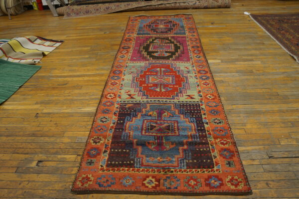 Vibrant geometric runner rug with teal, magenta, and rust colors displayed on rustic wood floors.