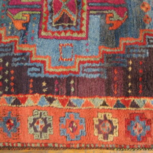 Richly colored, high-pile rug detail showing geometric patterns in blue, purple, orange, and magenta.