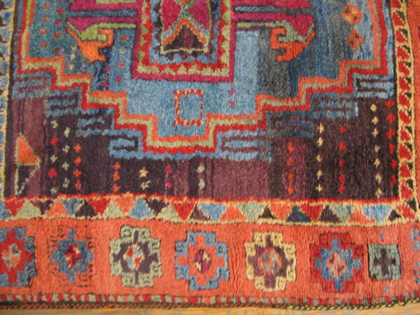 Richly colored, high-pile rug detail showing geometric patterns in blue, purple, orange, and magenta.