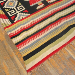 Red, black, and multicolor striped flatweave rug with geometric patterns displayed on rustic hardwood floors.