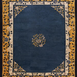 Navy blue rug featuring a large gold and cream border with intricate, stylized floral scrollwork.