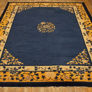 Blue rug with yellow and navy floral borders and a central floral medallion on wood flooring.