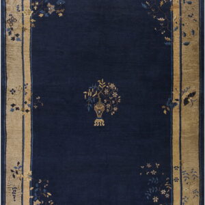 Navy rug with a central vase design and a wide tan border of blue and gold florals.