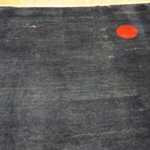 Dark blue rug featuring a red circular motif and a thin white and pink floral branch design.