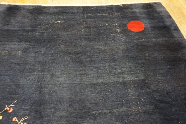 Dark blue rug featuring a red circular motif and a thin white and pink floral branch design.