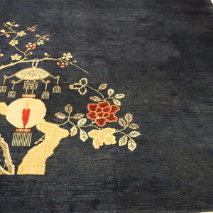 Deep blue rug featuring a large scenic pattern with red flowers, beige branches, and a white lantern.