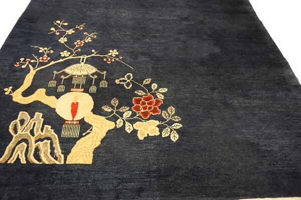 Deep blue rug featuring a large scenic pattern with red flowers, beige branches, and a white lantern.