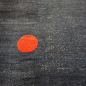 Dark blue textured rug featuring a large, solid red circle rests on light wooden plank flooring.