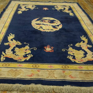 Navy blue rug with yellow dragon motifs and wide cream borders rests on worn wooden planks.