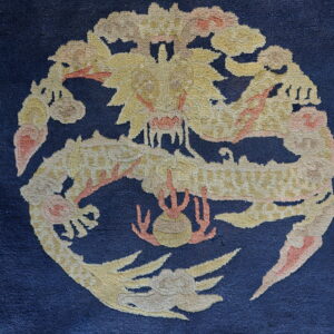 Navy blue rug with a circular, high-pile motif of a yellow and peach dragon.