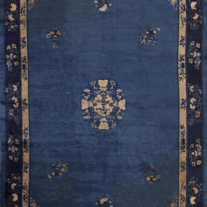 Blue low-pile rug with beige accents, featuring a floral center medallion and wide patterned borders.