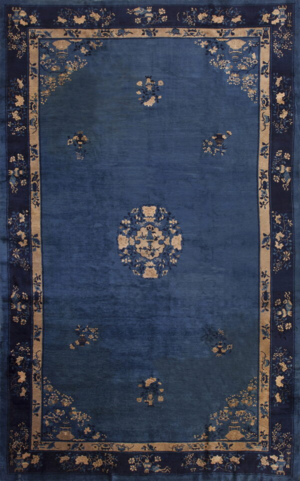 Blue low-pile rug with beige accents, featuring a floral center medallion and wide patterned borders.