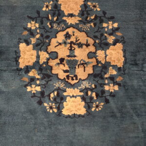 Plush, dark teal rug featuring a large tan and black circular floral medallion design.