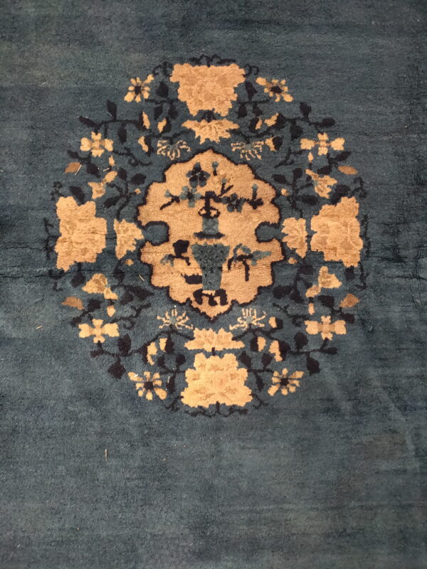 Plush, dark teal rug featuring a large tan and black circular floral medallion design.