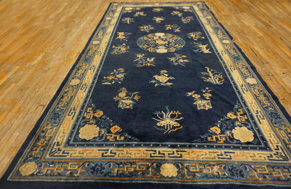 Navy blue rug featuring scattered tan and light blue botanicals and a geometric border on wood flooring.
