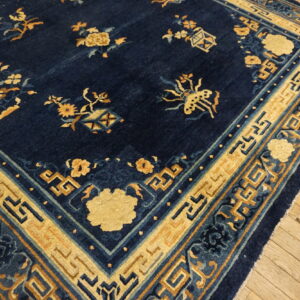 Deep blue rug with contrasting yellow-gold floral and geometric patterns visible on rustic wood flooring.