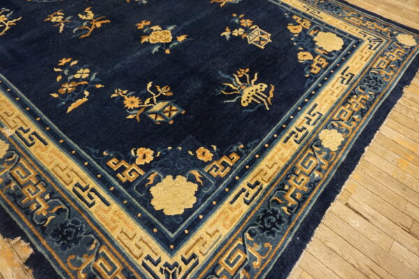 Deep blue rug with contrasting yellow-gold floral and geometric patterns visible on rustic wood flooring.
