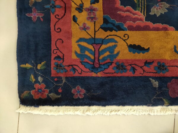 Navy rug with a multicolored floral and geometric design, yellow center field, red accents, and visible white fringe.