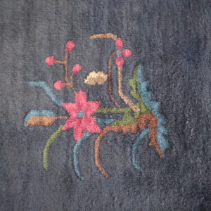 Dark blue medium pile rug detail featuring a pink and multicolored botanical design.