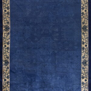 Rectangular deep blue rug featuring a tone-on-tone field and a wide beige border with blue floral designs.