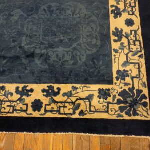 Dark blue high-pile rug with subtle tone-on-tone field and wide tan floral border on wood floors.
