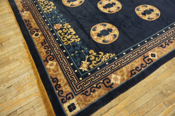 Dark blue rug featuring tan medallions and a wide, multi-colored border on rustic wood planks.