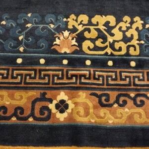 Detailed view of a high-pile rug with navy, gold, and brown colors in floral and Greek key borders.