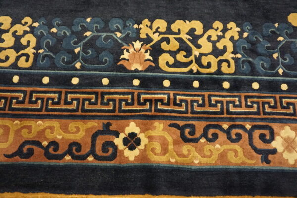 Detailed view of a high-pile rug with navy, gold, and brown colors in floral and greek key borders.