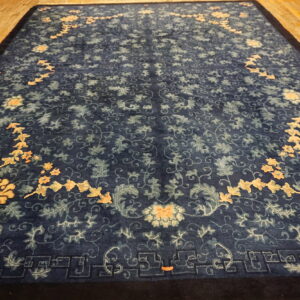 Traditional dark blue rug with large peach and light blue floral designs on wood flooring.