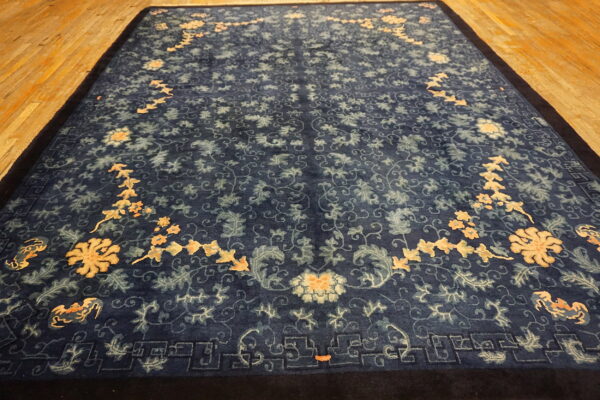 Traditional dark blue rug with large peach and light blue floral designs on wood flooring.
