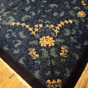 Navy blue rug features intricate floral and vine patterns in peach and pale green on hardwood floors.