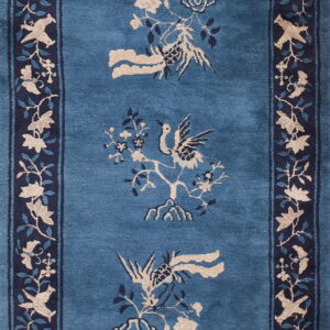 Blue rug with a navy border displays central beige and blue stylized birds and flowering branches.