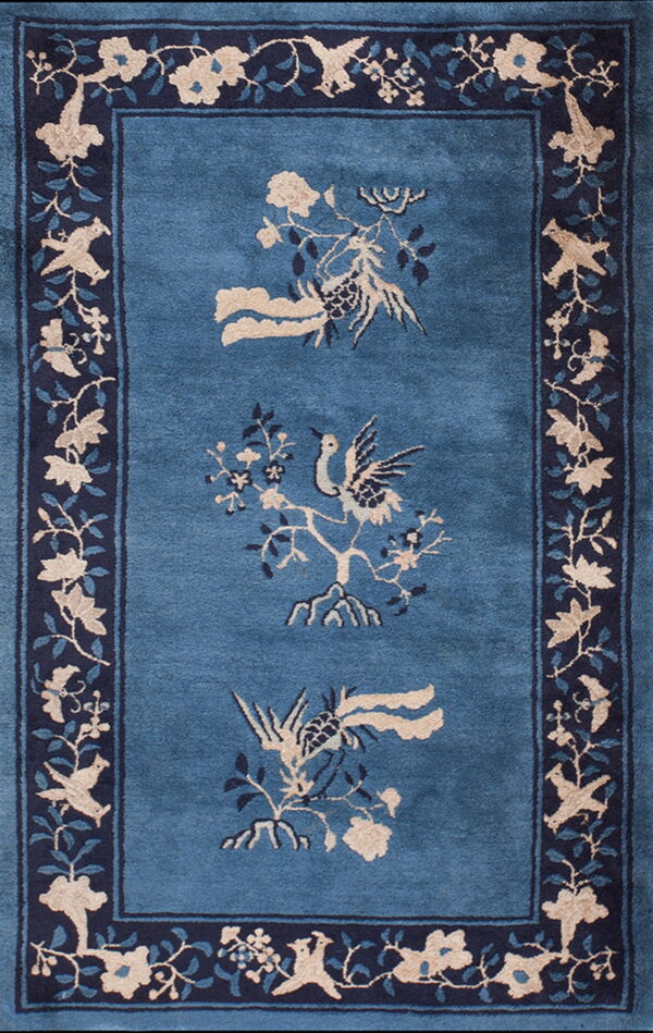 Blue rug with a navy border displays central beige and blue stylized birds and flowering branches.