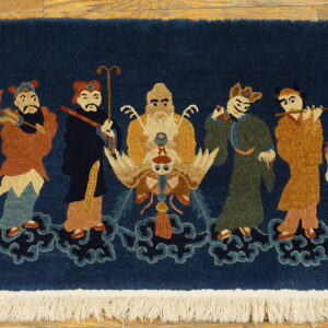High-pile navy rug with a scene of nine colorful figures on clouds, finished with white fringe on wood floor.