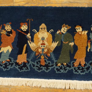 Navy rug with rust, green, and cream figures standing on stylized blue clouds over wood flooring.