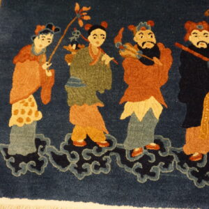 Detailed view of a blue rug with a figural pattern in rust and green, resting on honey-colored wood floors.