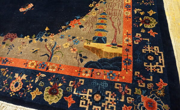 Detailed navy rug corner showing a pagoda scene, flowers, and multi-colored geometric borders.