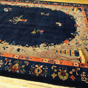 Navy rug with a beige lobed field, colorful floral and geometric borders, resting on wood floors.