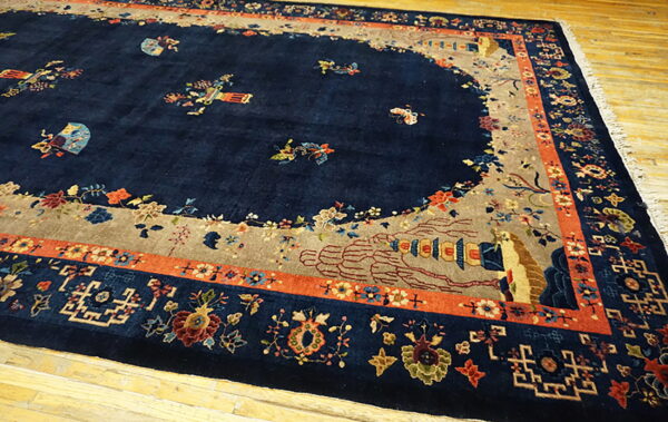 Navy rug with a beige lobed field, colorful floral and geometric borders, resting on wood floors.