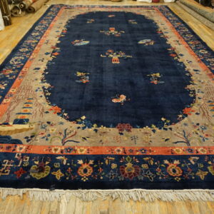 Lustrous navy rug featuring a floral and scenic pagoda pattern bordered in terracotta on light wood floors.