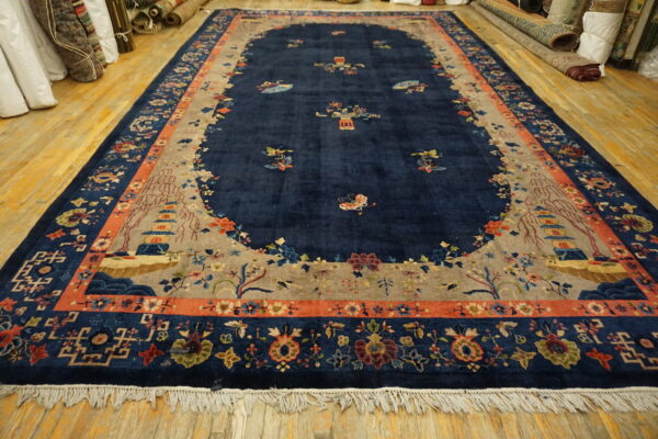 Lustrous navy rug featuring a floral and scenic pagoda pattern bordered in terracotta on light wood floors.