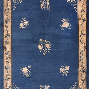 Blue rug with scattered beige flowers and corner sprays, framed by a wide tan floral border.