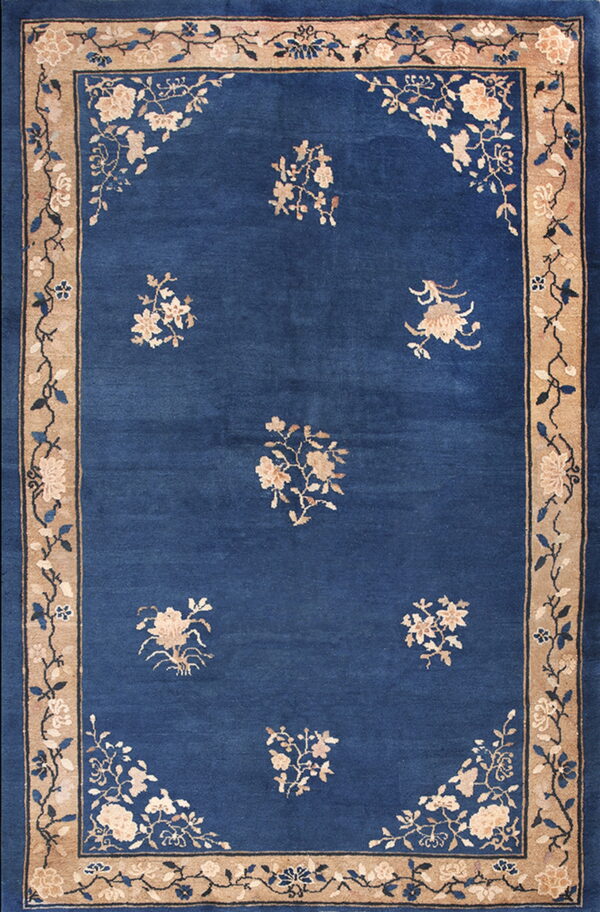 Blue rug with scattered beige flowers and corner sprays, framed by a wide tan floral border.