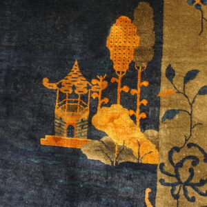 Dark blue rug detail featuring an orange pagoda, brown trees, and a vertical khaki-colored border design.