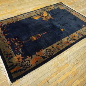 Navy rug with orange and blue floral motifs bordering the field on distressed wood flooring.